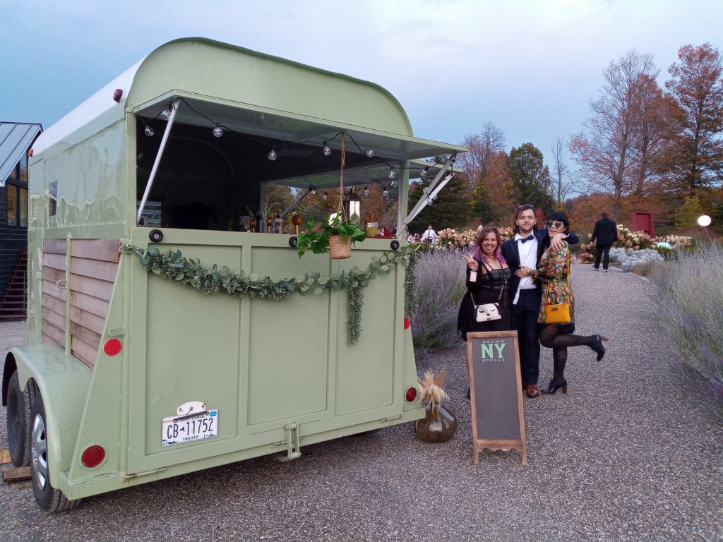 3 individuals drinking cider next to the mobile bar